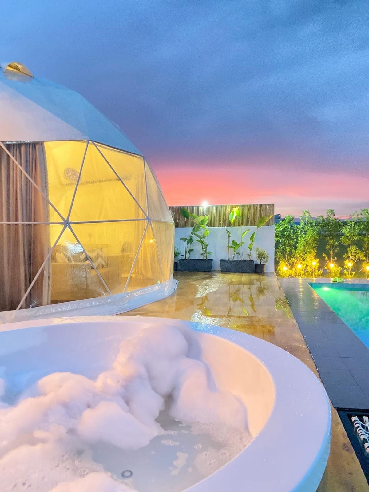 Dome 1 lit from within at dusk, jacuzzi in the foreground