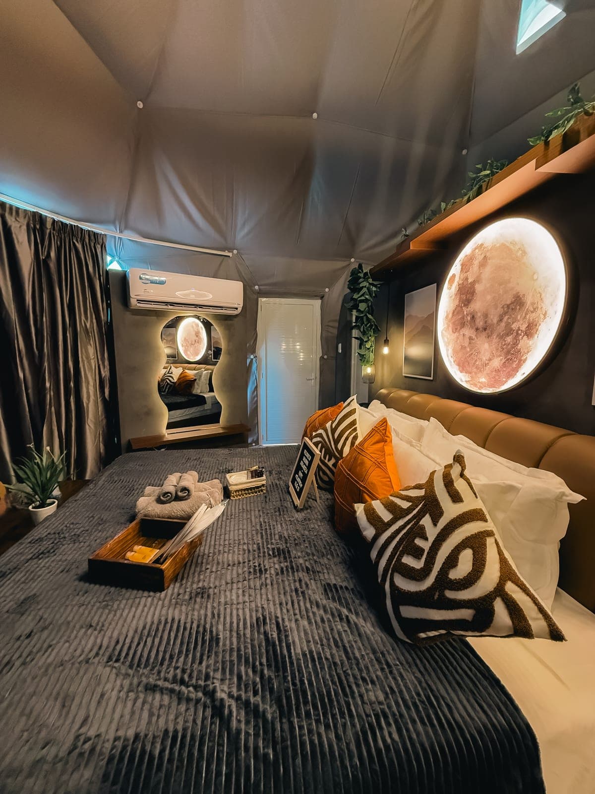 Dome 2: the king bed in darker tones beneath a round moon lamp