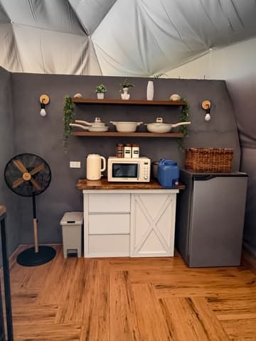 The indoor kitchenette: microwave, kettle, fridge and open shelving